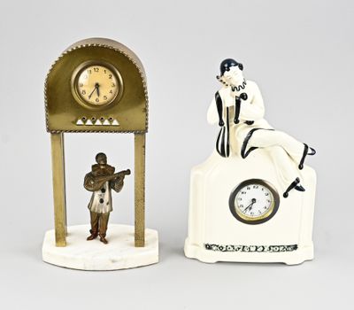two figurines of people sitting on top of a clock