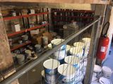 de nombreux seaux de peinture posés sur une étagère dans un entrepôt