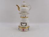 a small white teapot with a gold trim on it