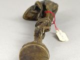 a small brass object with a tag on it