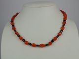 an orange and black beaded necklace on a white mannequin