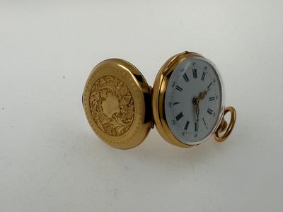 a gold pocket watch sitting on a white surface