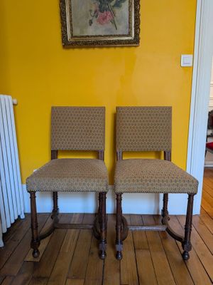 pair of upholstered chairs in front of a painting in a yellow room