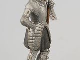 statue of a man in armor holding a sword on a wooden base