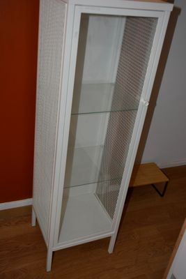 une armoire blanche avec une porte vitrée, dans un coin de la pièce