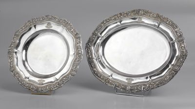 a pair of silver plated dishes on stands on a grey surface