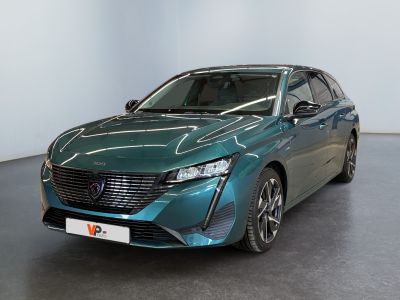 La voiture verte est garée dans une grande pièce aux murs blancs.