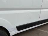 the side of a white van with black trims parked in a parking lot