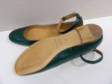 pair of green leather shoes with buckles on a white surface