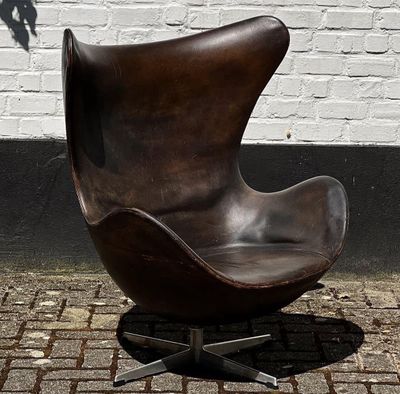 un fauteuil en cuir marron posé sur un trottoir en briques