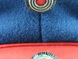 a red and blue hat with a silver button on it