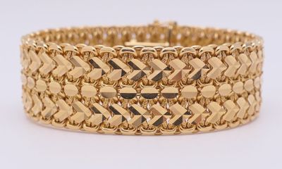gros plan d'un bracelet en or sur une surface blanche