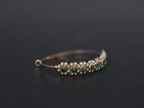 a close up of a gold ring with green stones