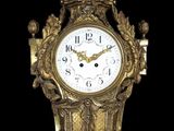 une horloge dorée surmontée d'une couronne, sur fond noir