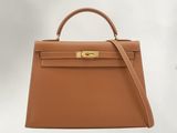 a brown hermes handbag with gold hardware on the handle