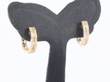 un gros plan sur une paire de boucles d'oreilles créoles en or posées sur un présentoir noir