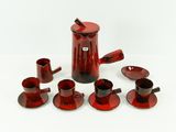 une cafetière rouge et des tasses posées sur une table blanche