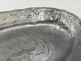 a silver plate with a picture of a woman and a bird on it