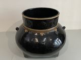 a black vase with gold decoration on it on a table