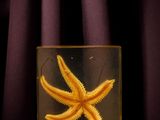a yellow starfish in a clear glass on a purple surface