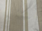 beige and white striped fabric on a bed with a white pillow