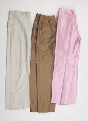 trois paires de pantalons sont alignées sur une surface blanche