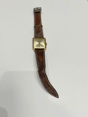an image of a watch on a white surface with a brown strap
