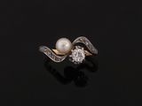 a pearl and diamond ring on a black surface