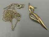 two pieces of jewelry are sitting on a table next to a pair of scissors