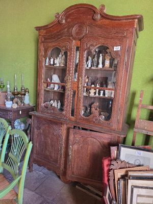 un vaisselier en bois dans un salon vert, avec une table et des chaises