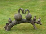 une sculpture représentant des canards perchés sur une branche d'arbre dans l'herbe