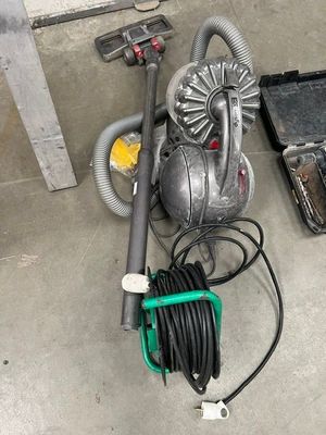 un aspirateur et un tuyau posés par terre à côté d'une boîte à outils