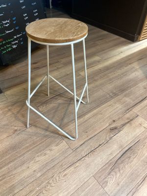 tabouret en métal blanc avec une assise en bois, placé devant un tableau noir