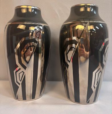 une paire de vases noirs et argentés posés sur une surface blanche