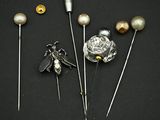 trois broches ornées de perles et d'une abeille sur fond noir