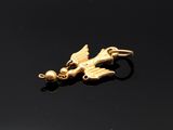 an image of a gold bird charm on a black surface