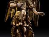 statue d'un ange tenant un oiseau, posée sur un socle dans une pièce sombre
