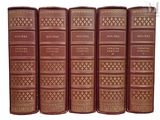 six vieux livres sont alignés sur une surface blanche