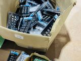 une boîte de télécommandes posée par terre à côté d'une pile d'autres télécommandes