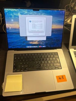 two laptops sitting on a desk with sticky notes on them