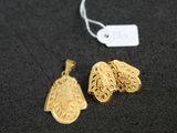 deux pendentifs en or posés sur une surface noire, accompagnés d'une étiquette de prix