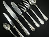 cinq fourchettes, une cuillère et un couteau posés sur une table noire