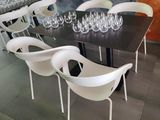 a black table with white chairs and wine glasses on it