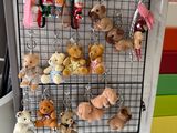 many stuffed animals hanging on a wire rack on the refrigerator