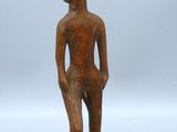 une petite statue en bois représentant un homme debout sur un socle en bois