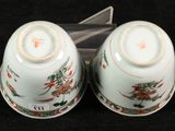 two white bowls with flowers on them on a black surface