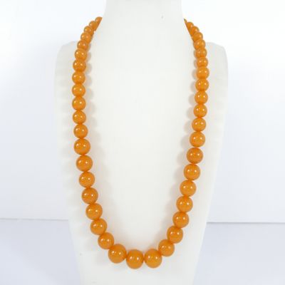 a close up of an orange beaded necklace on a mannequin