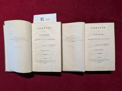 trois livres ouverts posés sur une table recouverte d'un tissu rouge