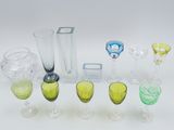 many different colored glasses and vases sitting on a table