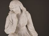 a white statue of a woman sitting on a stool